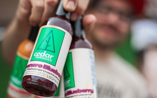 Bottles of hot sauce held in one hand